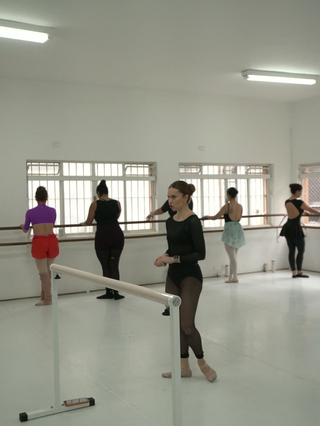 Sala de ballet da Escola Paulista de Dança com barras, janelas amplas e a turma em aula