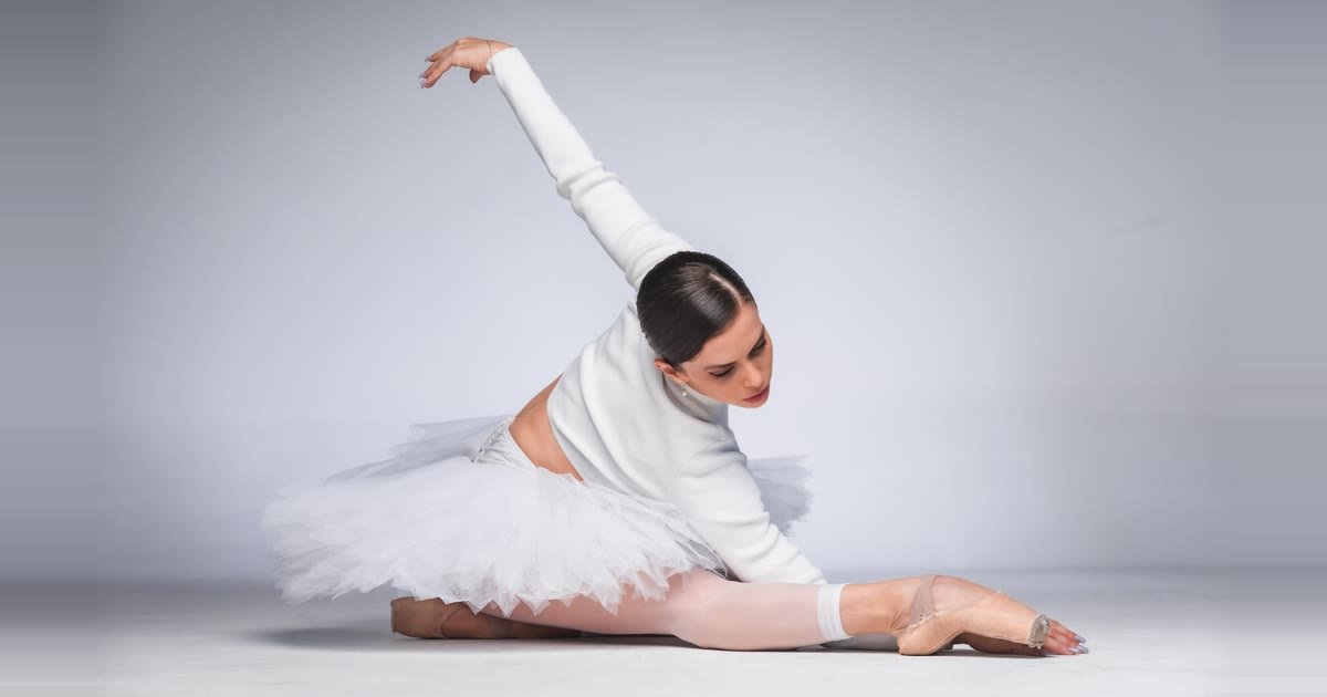 Renata Bardazzi, bailarina do Balé da Cidade de São Paulo, sentada no chão, alongando o tronco sobre a perna estendida
